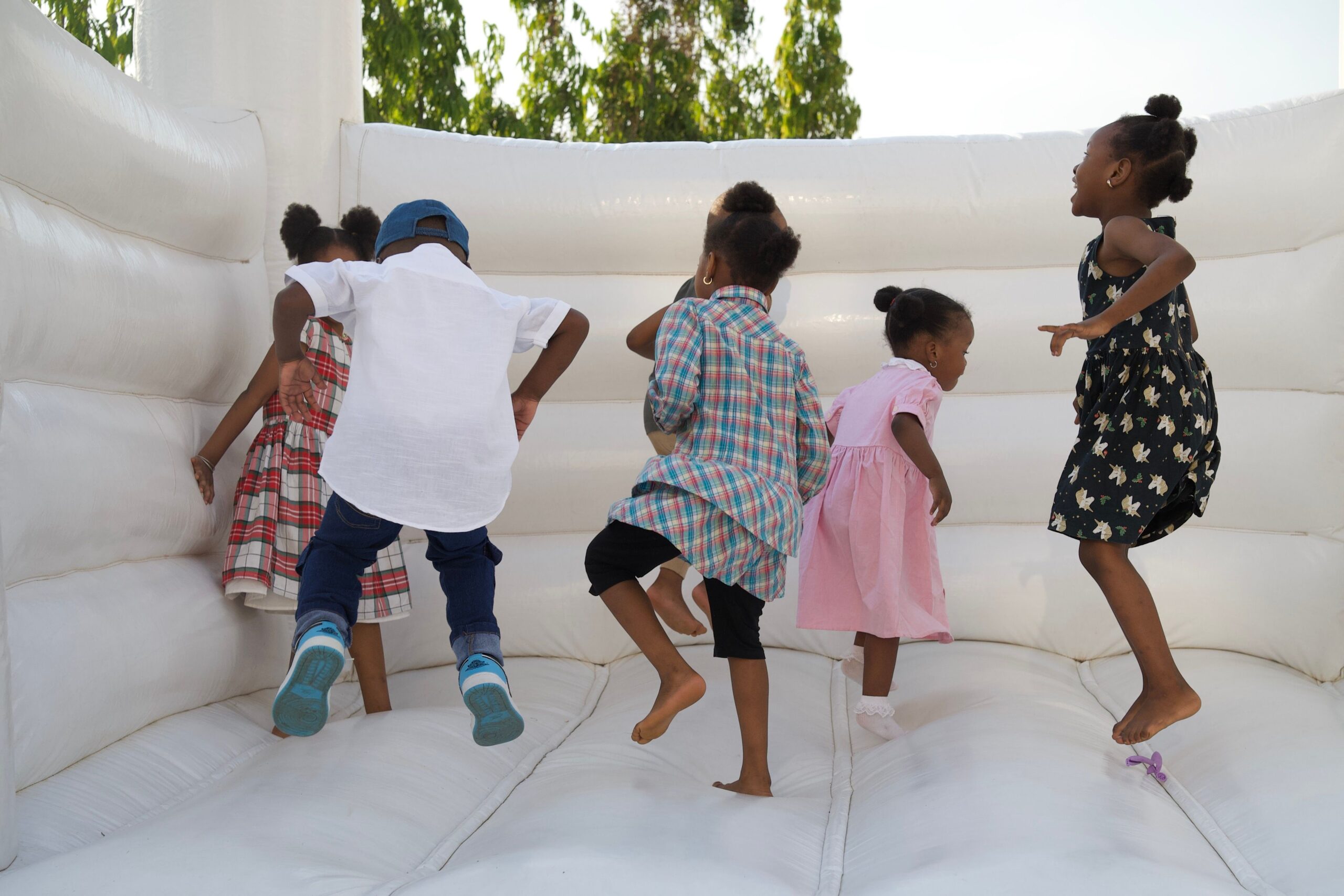 Enfants jouant sur un château gonflable blanc en extérieur pour une fête d'anniversaire
